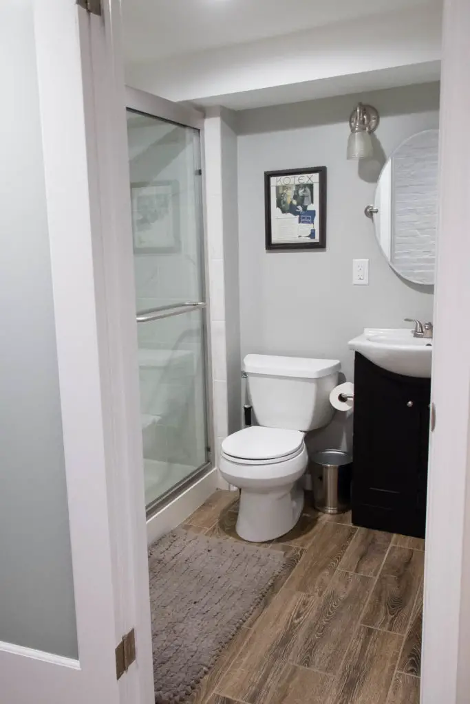 Below-grade basement bathroom addition with faux wood floors and privacy glass door. | EffieRow.com #BuildWhatYouLove