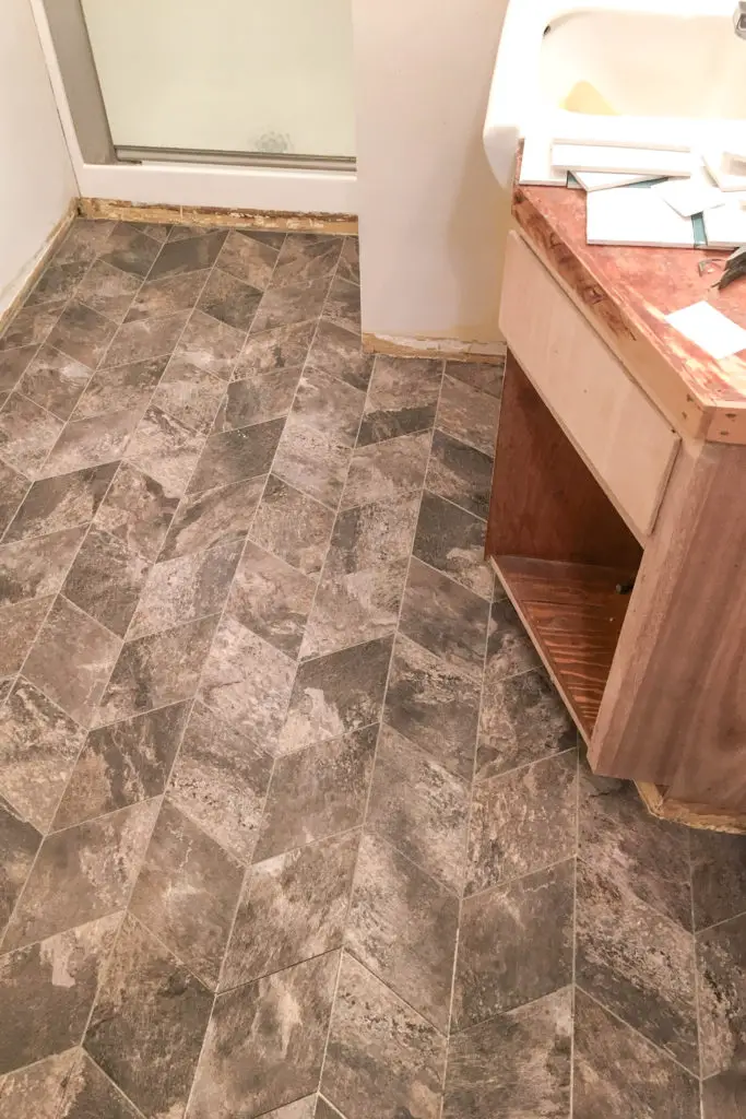 Grouting vinyl tiles in a basement bathroom.