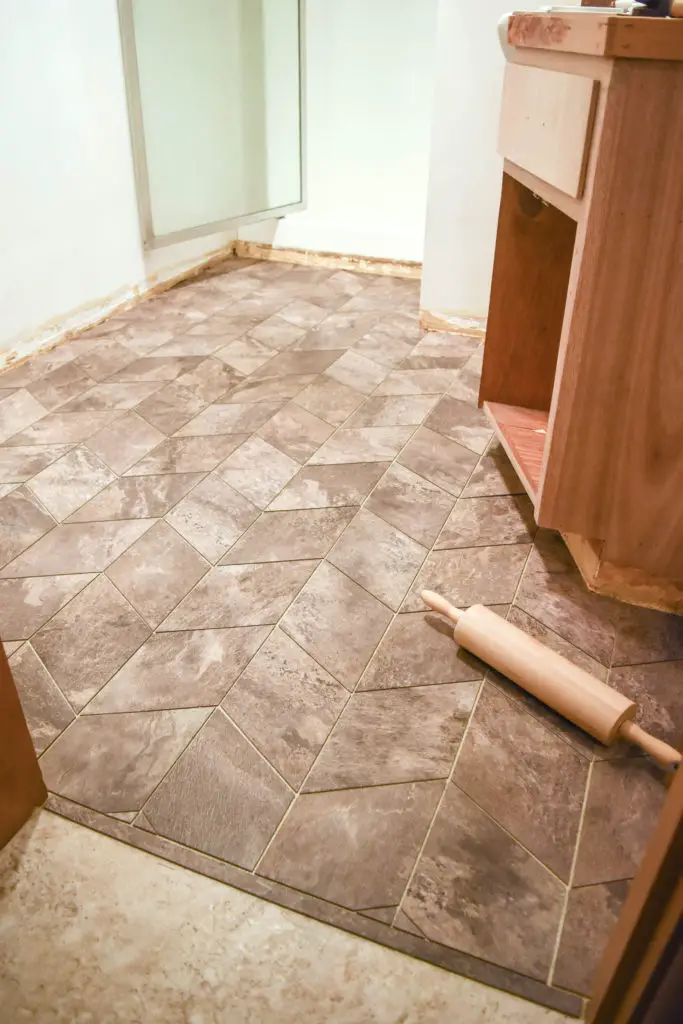 How to lay custom vinyl tile floors - great option for a bathroom renovation and easy way to cover up existing floors! Cut vinyl tiles to shapes and lay them in a pattern.